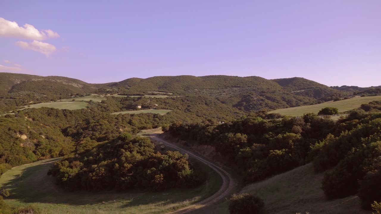 Pan shot of amazing landscape of hills during sunset on a clear sky day.
