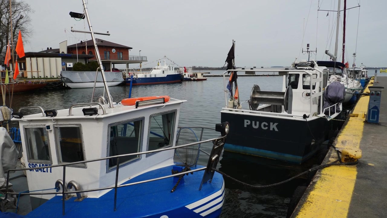 Barche tradizionali colorate ormeggiate nel tranquillo porto di Puck, Polonia. Una vista panoramica del porto della baia baltica che cattura l'autentica atmosfera marittima lungo la costa polacca.
