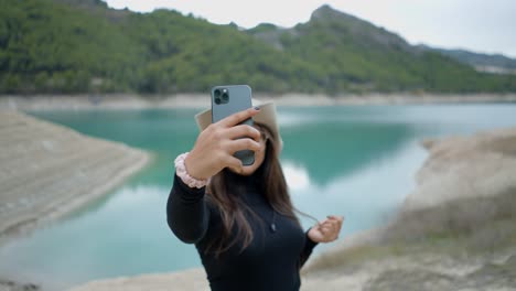 una mujer tomando una selfie junto a un lago.