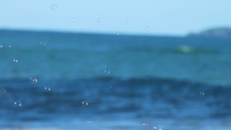 gentle ocean waves and floating bubbles under clear skies at charlesworth bay beach, coffs harbour. captured in bright daylight