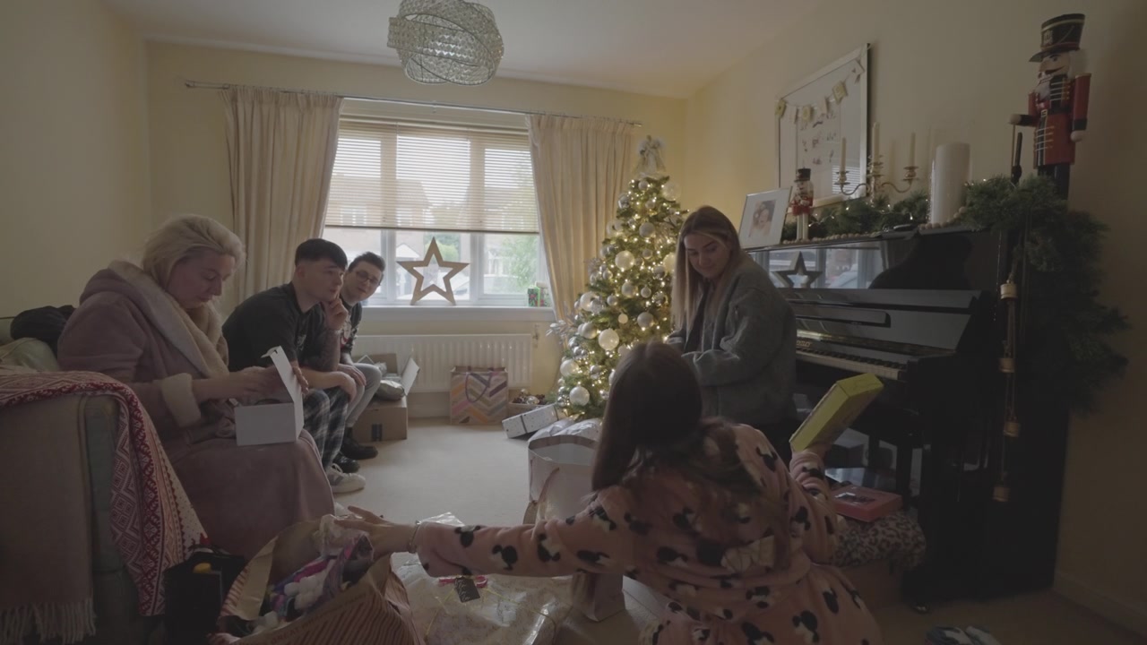 Familiebijeenkomst op kerstochtend, cadeaus uitwisselend, gelukkige herinneringen.