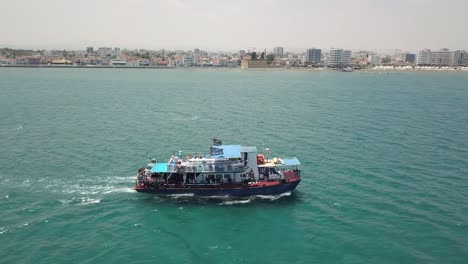 Toma-De-Seguimiento-Del-Viaje-En-Barco-Navegando-Con-Turistas-En-El-Hermoso-Mar-Tranquilo-De-Larnaca,-Chipre