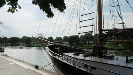 close up shot of old huge sailing boat anchored at shore and cruising electric boats in background