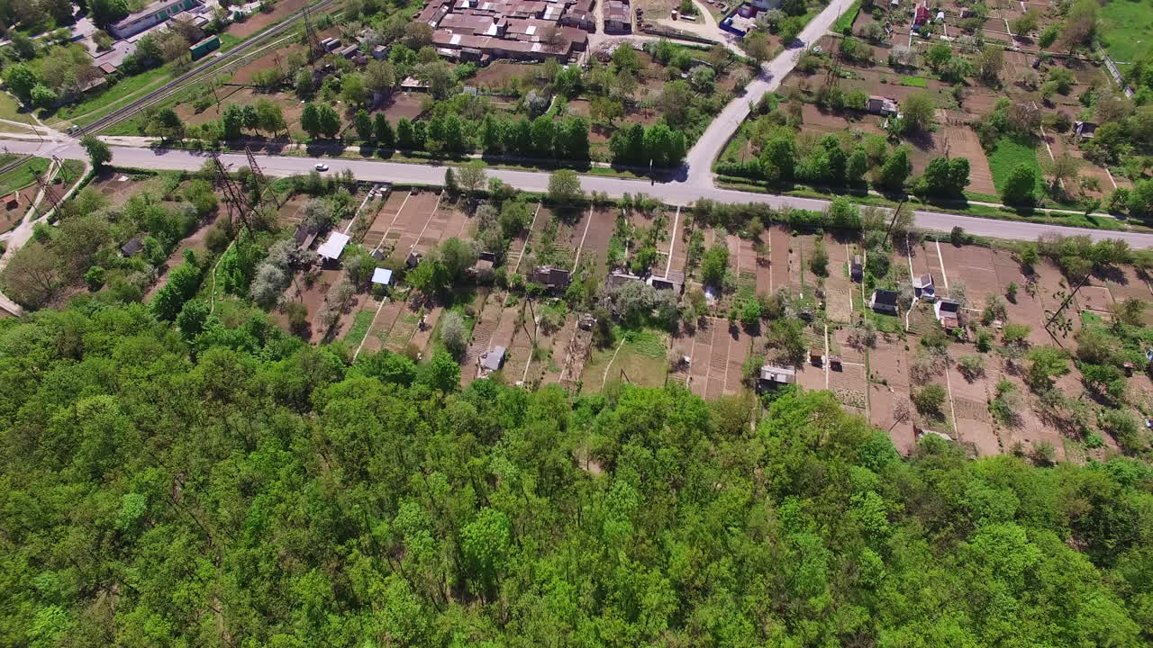Footage over the green forest, industrial zone and city residential area. Aerial perspective on the urban territory on sunny daytime.