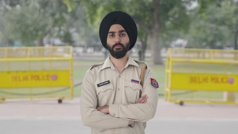 confident sikh indian police man standing crossed hands