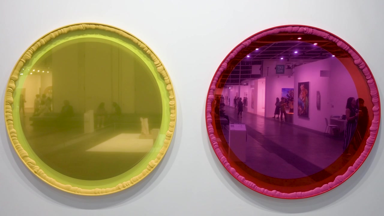 Attendees are seen reflected on an artwork hanging on the wall for sale during the Art Basel Hong Kong contemporary art fair show event.