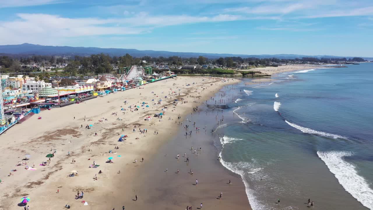 vista larga toma de drones del paseo marítimo de la playa de santa cruz mientras el dron vuela hacia atrás y lejos de las multitudes en la playa y el paseo marítimo