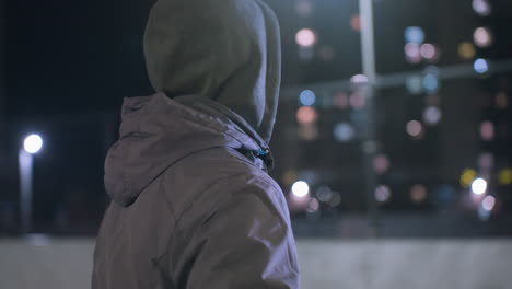 primer plano de un atleta entrenando por la noche, haciendo malabarismos con una pelota de fútbol con su rodilla, persiguiendo la pelota a medida que se aleja, enmarcado por luces de calles urbanas y edificios residenciales en el fondo