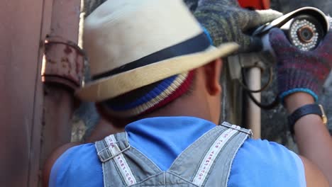 vista trasera en cámara lenta de un adulto joven con sombrero fedora revisando, ajustando e inspeccionando la cámara de seguridad