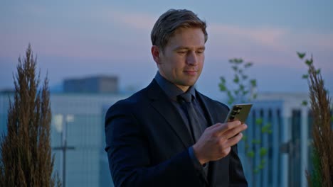 smiling man caucasian professional looking at his phone on a rooftop terrace in seoul at sunset - a parallax close-up shot