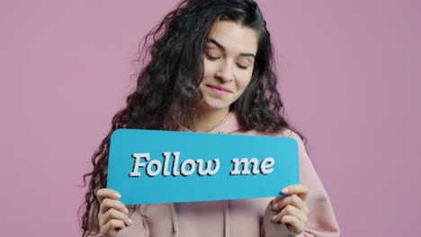 woman holding a sign that says 'follow me'