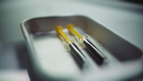 syringes with a dark liquid on a medical tray