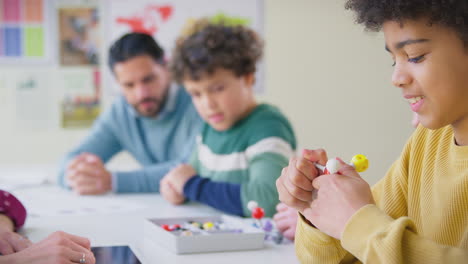 multi-cultural students with teachers in classroom studying molecular model in science class