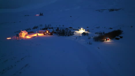 little orange lit church next to a hotel in a lot of snow in iceland at night