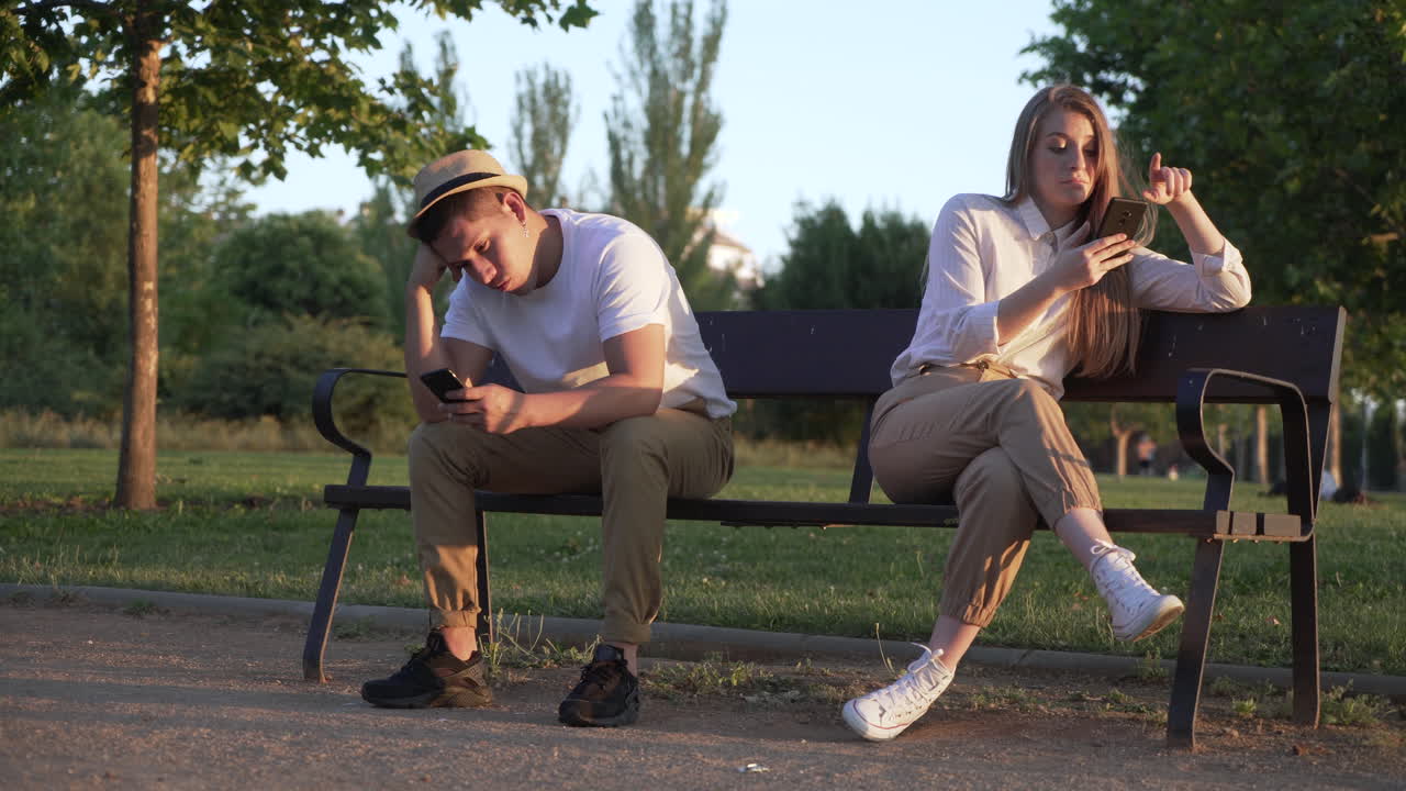 boring couple using their mobile phones in a public park