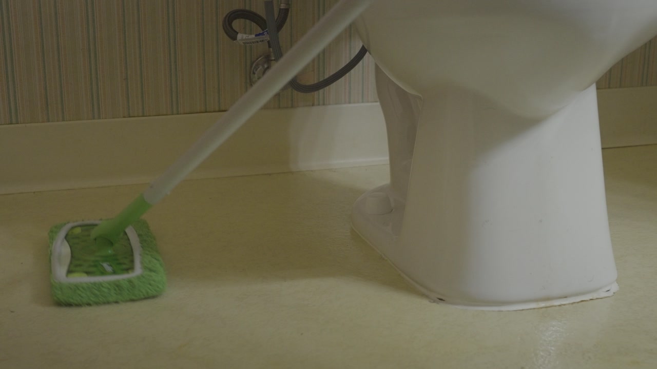 Slow movement of mopping a dirty bathroom floor.