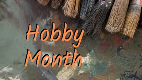 Animation-of-hobby-month-text-in-orange-over-oil-paint-and-paintbrushes-on-palette