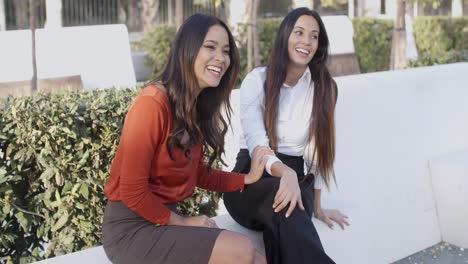 vivacious young women sitting outdoors laughing