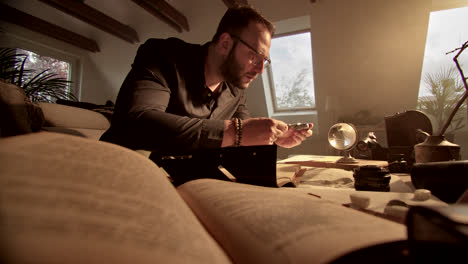 man examining an item with a magnifying glass at home