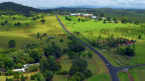 aerial view of countryside road among green fields in atherton tablelands, queensland, australia - drone shot