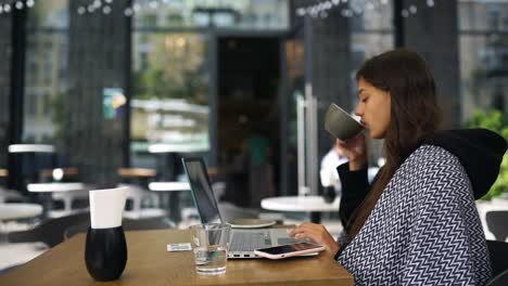 mujer trabajando en una computadora portátil en un café