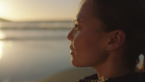 retrato de cerca de una hermosa mujer joven disfrutando de una tranquila puesta de sol tranquila mirando relajada pensativa mujer caucásica en la playa costera del océano