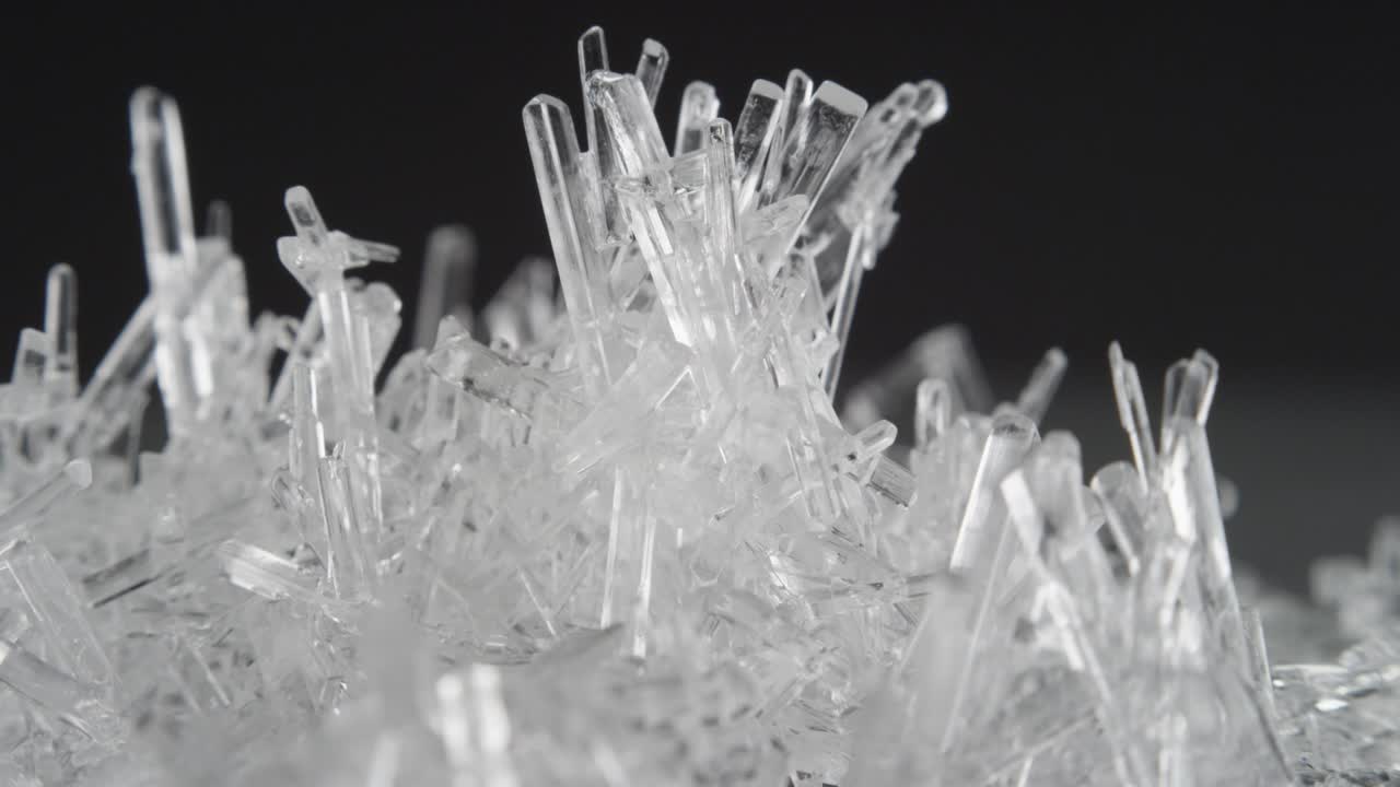 macro disparo de cristales de sal claros giran contra el fondo negro y brillan