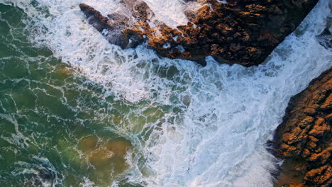 rough sea waves washing seashore stones. top drone view ocean crashing on rocks