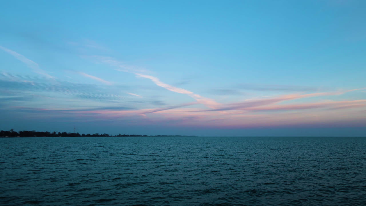 드론은 푸른 시간에 가장자리에 해안 숲과 함께 평온한 빈 물 위에 밀어 넣습니다.