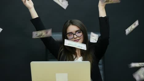 beautiful young businesswoman is counting money, fanning herself with dollars, laughing and throwing them in the air