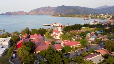 aerial view rising over roman catholic motael church and urban buildings, streets and trees in capital city of dili, east timor