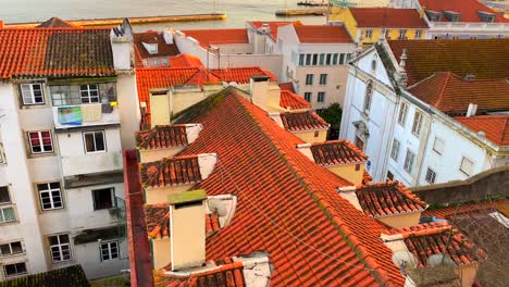 beautiful sunset view from a window on a river with moving boats with traditional orange rooftops and incredible sky in lisbon city portugal, 4k tilting up