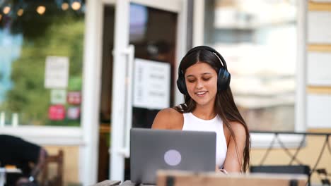 mujer joven trabajando en una computadora portátil en un café