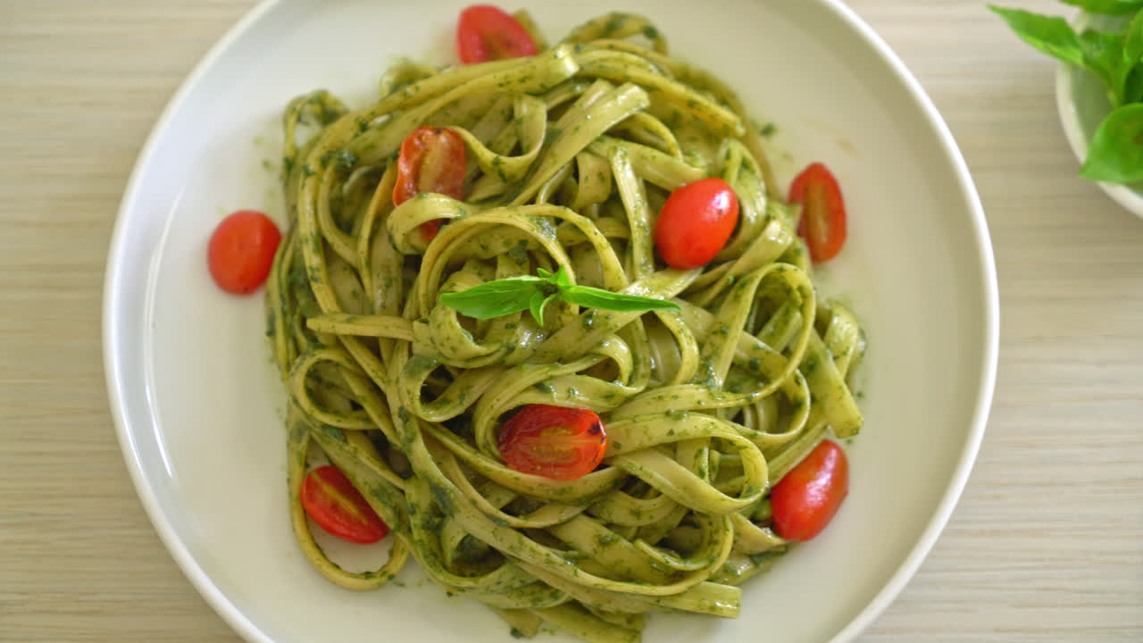 espaguetis fettuccine con salsa pesto y tomates - estilo de comida vegana y vegetariana