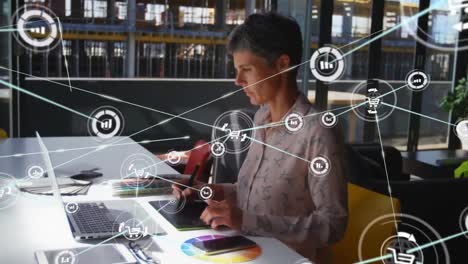 Animation-of-network-of-connections-with-icons-over-businesswoman-using-graphic-tablet