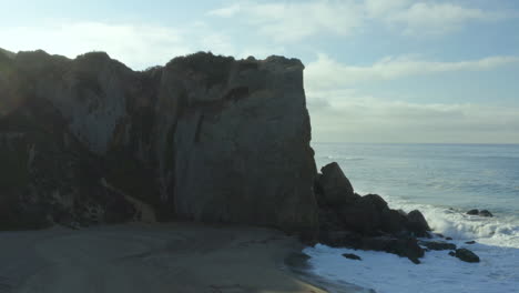 aerial dolly towards the rocks where large waves are crashing