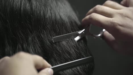 man gets modern haircut at barber, combing and cutting hair closeup