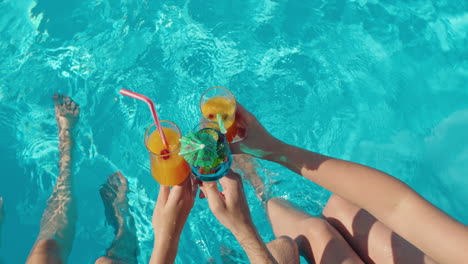 friends toasting cocktails by the pool