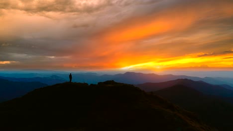 the man standing on the mountain against the beautiful sunset