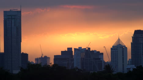 Goldener-Sonnenuntergang-Im-Zeitraffer-Hinter-Wolken,-Skyline-Der-Wolkenkratzer-In-Der-Silhouette