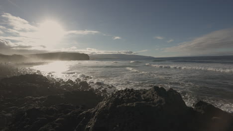 Pan-of-ocean-waves-washing-over-rocky-coast-at-sunset-at-the-Azores