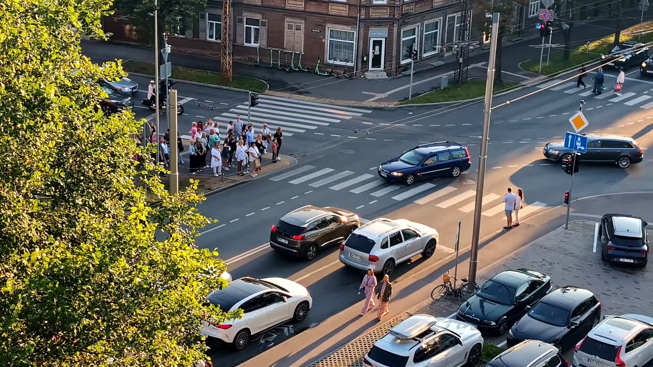 Overview of a busy street intersection with cars and pedestrians under clear skies in the city