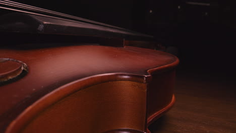 mysterious close up macro shot of a violin. slider shot down from the neck across the body. unique perspective. probe lens.