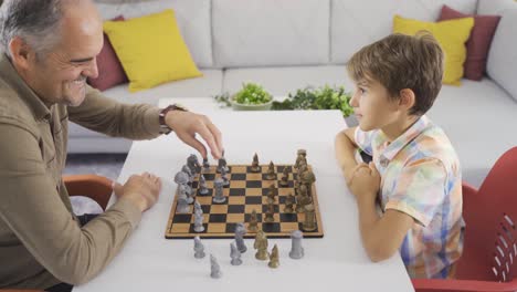 el abuelo y el nieto están jugando al ajedrez. el niño inteligente gana al ajedrez.