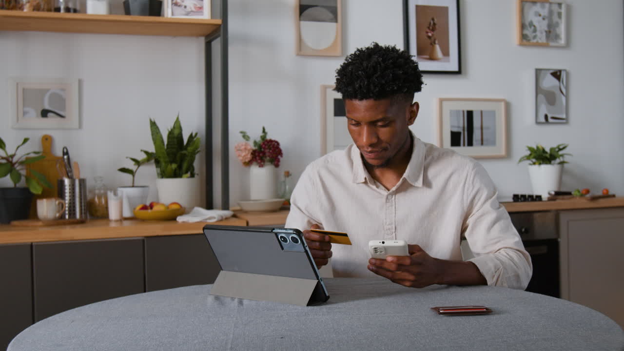 Man Shopping Online with Tablet and Credit Card in Kitchen