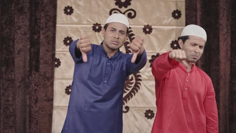 two muslim men showing thumbs down to the camera