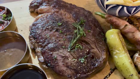 a rare steak garnished with herbs, surrounded by condiments and vegetables, captured in natural lighting on a wooden table