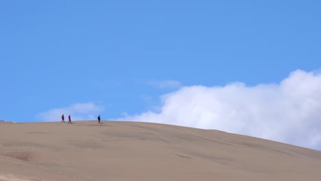 people hiking over sand dunes on a sunny day