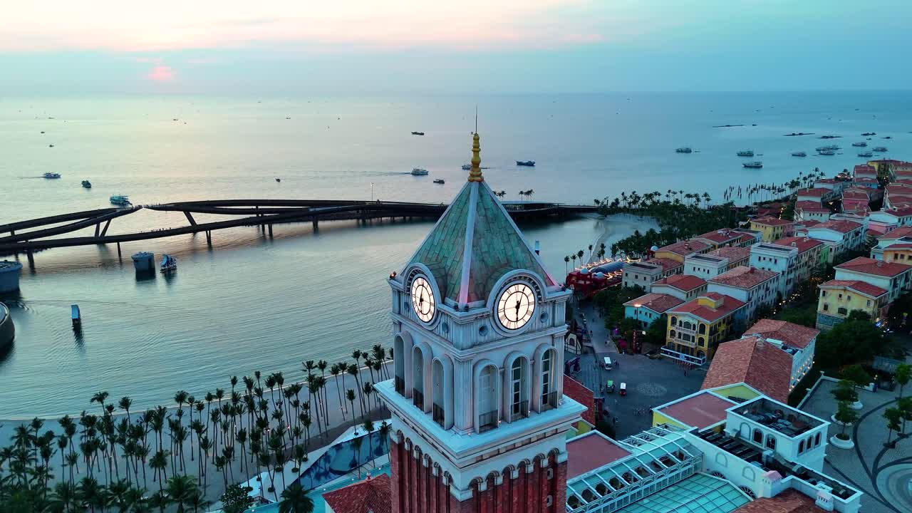 Aerial: Central Village St. Mark's Campanile Clock Tower at sunset, a fake Italian city in Phu Quoc Island, Vietnam, parallax drone shot