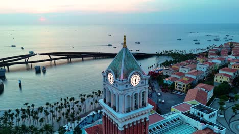 aerial: central village st. mark's campanile clock tower at sunset, a fake italian city in phu quoc island, vietnam, parallax drone shot